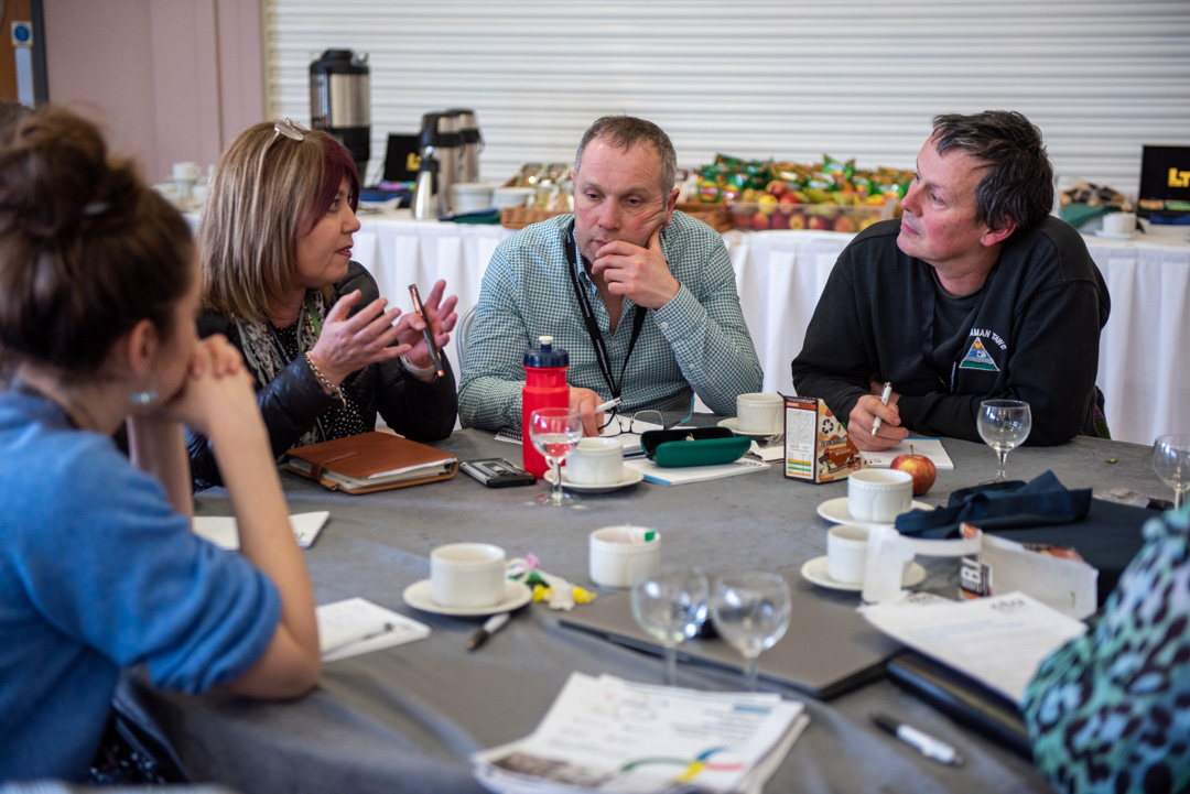 four people sat around a conference table talking