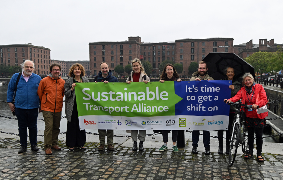 Group of people holding a long green sustainability banner on the Liverpool waterfront