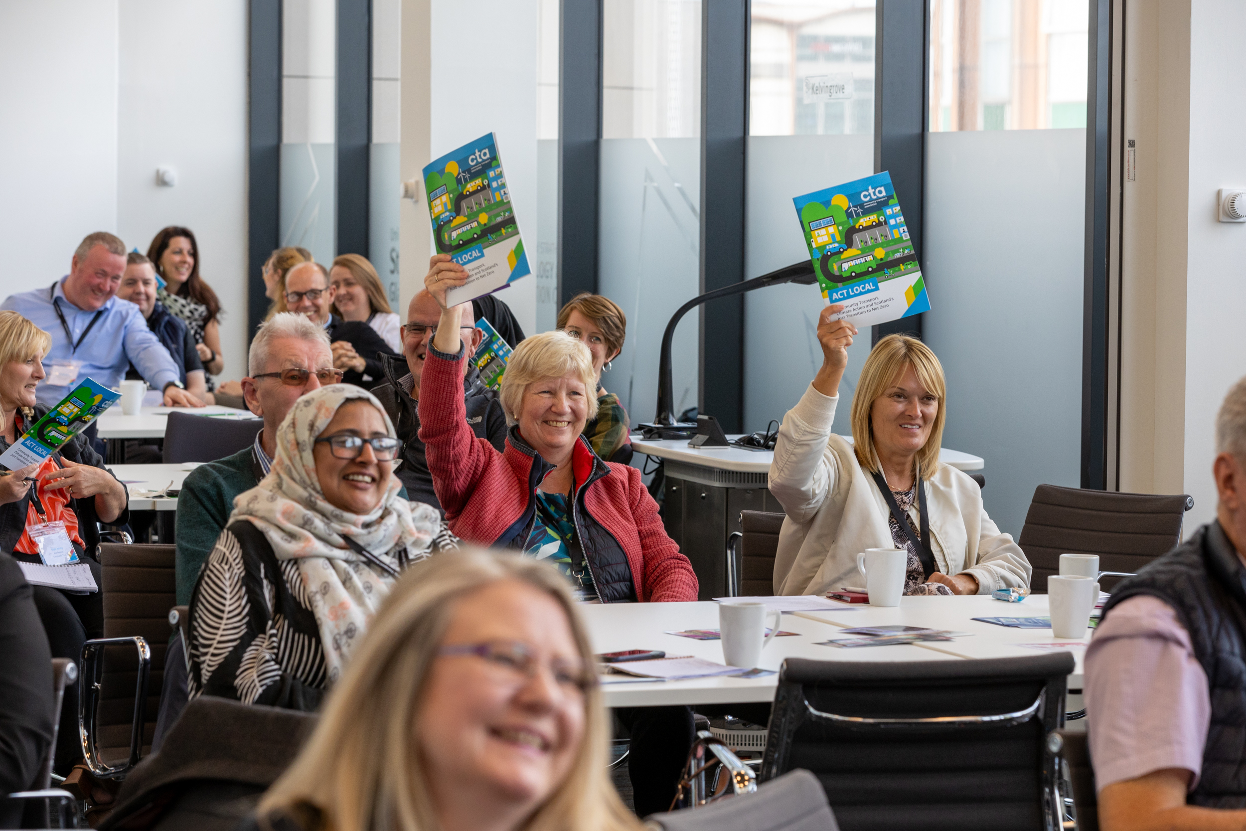 conference setting showing cta members holding cta report brochure aloft and smiling 