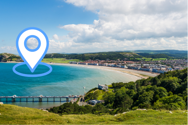 photo of a Welsh seaside town with a graphic location pin in blue and white 