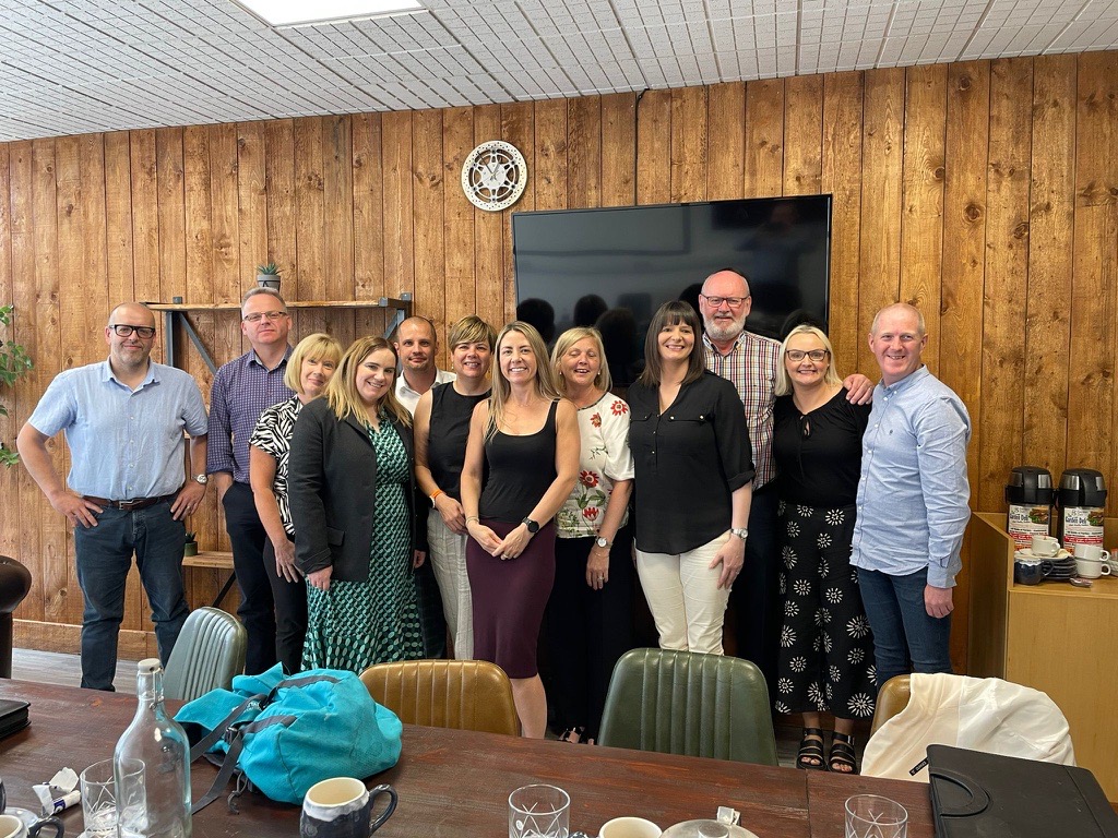 wood paneled room with group of smiling people from Northern Ireland smiling at the camera 