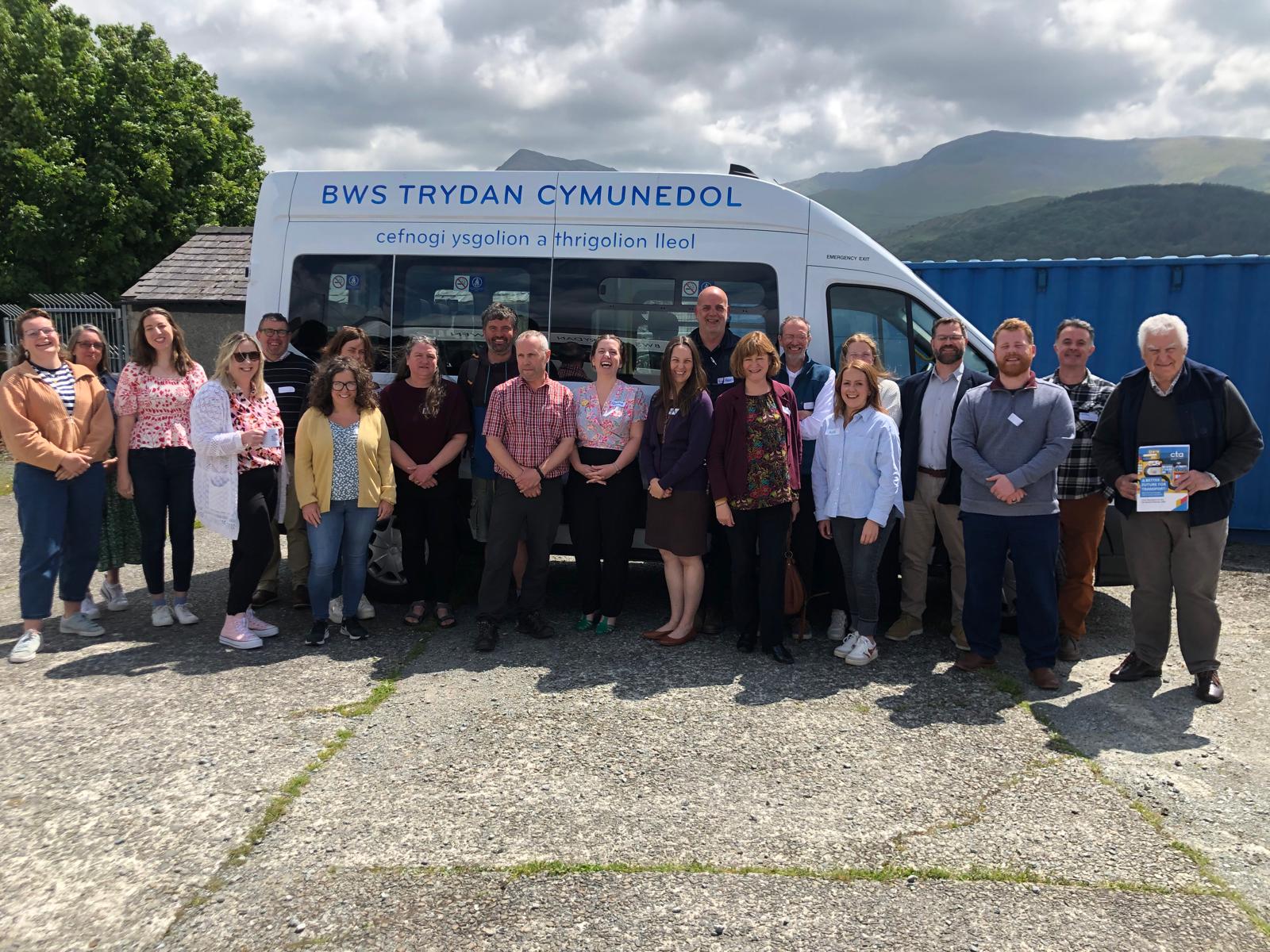 Group of Welsh CTA members and staff standing in front of a white liveried minibus, smiliing.