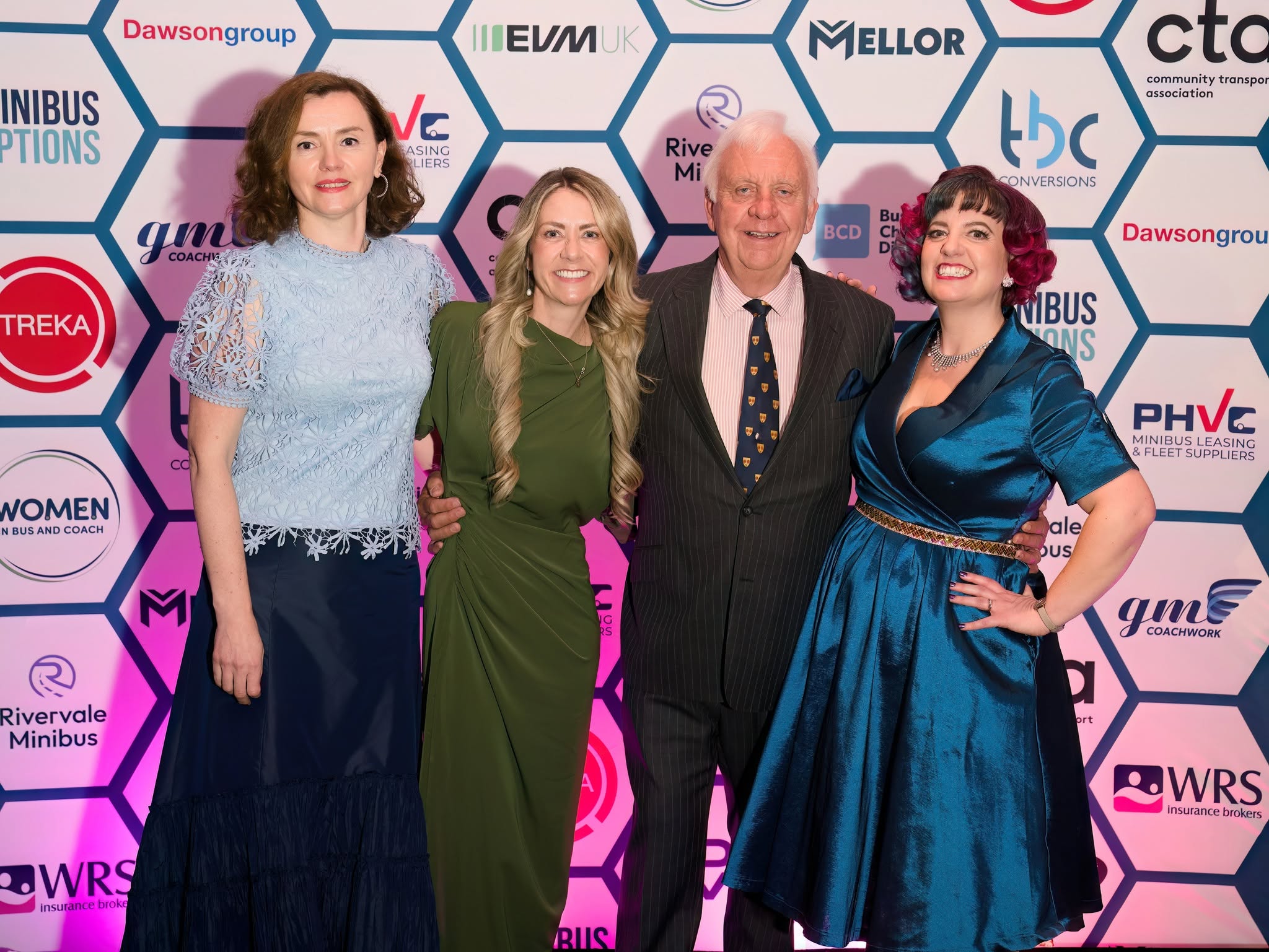 A group photo with everyone in formal wear posing against a CT26 backdrop