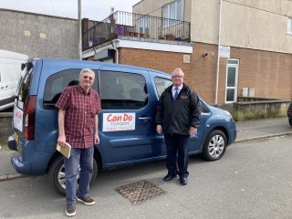 Two men stand in front of a blue accessible car with the words 'Can Do' on the side