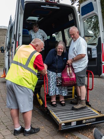 People-helping-woman-out-of-minibus