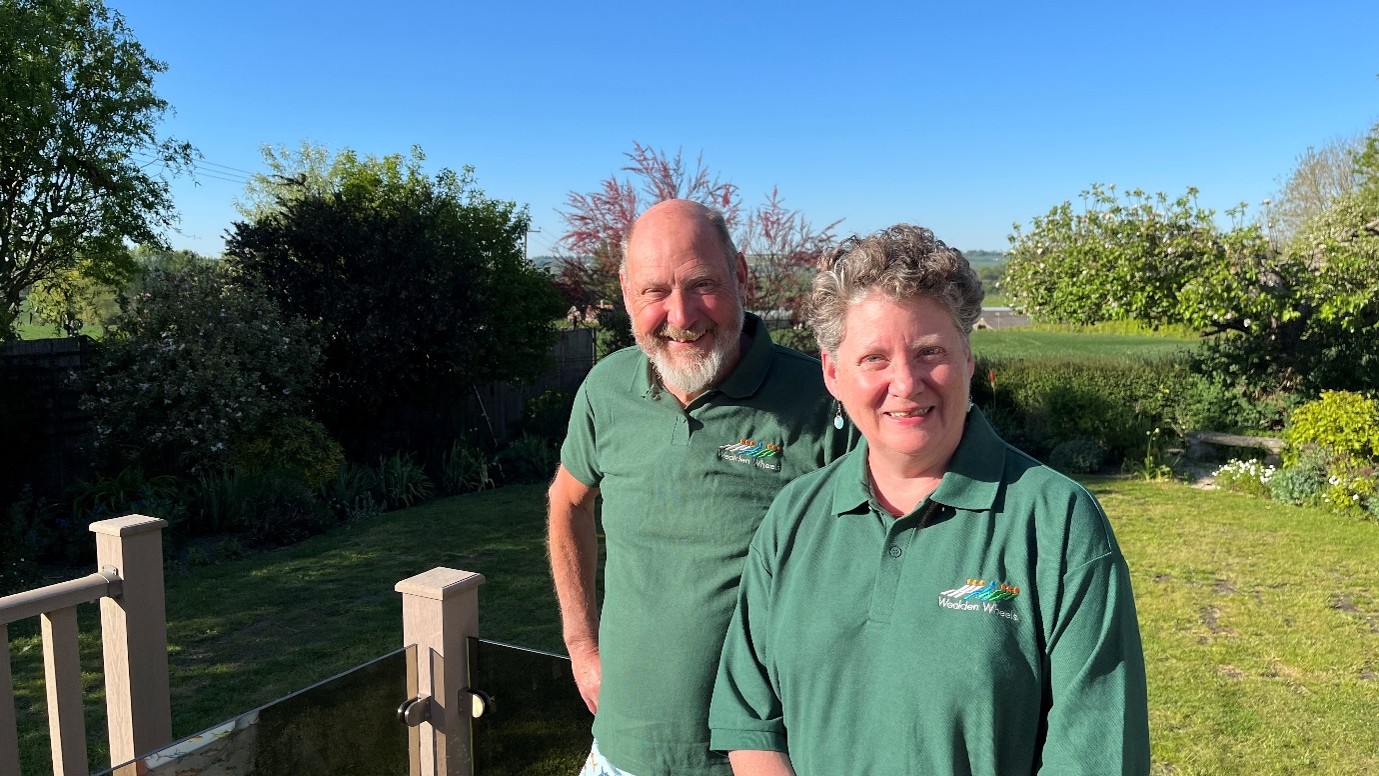 An image of Karen and Cliff Clark standing outside in their volunteer uniform