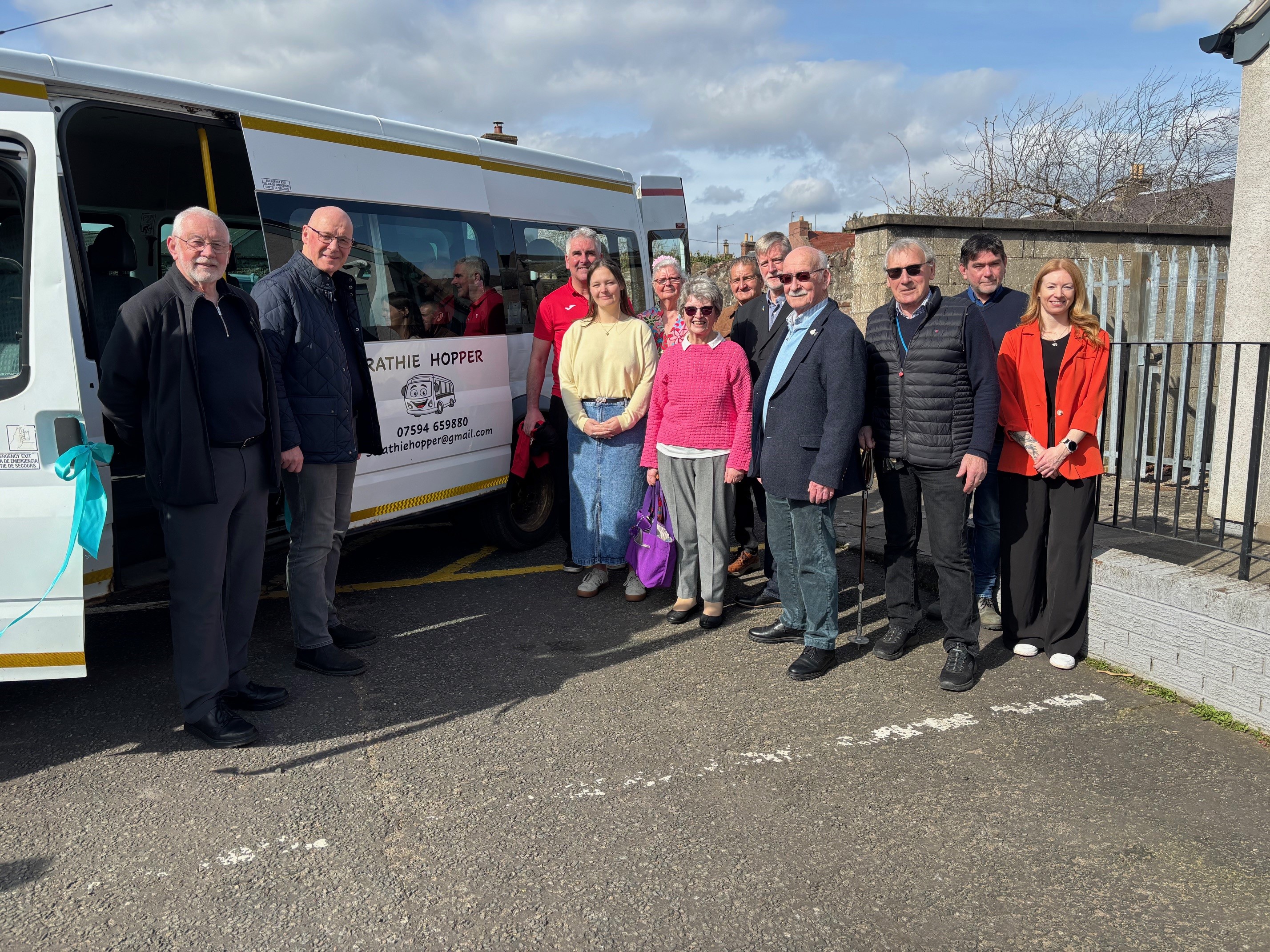 a variety of people standing outside the Strathie Hopper minibus