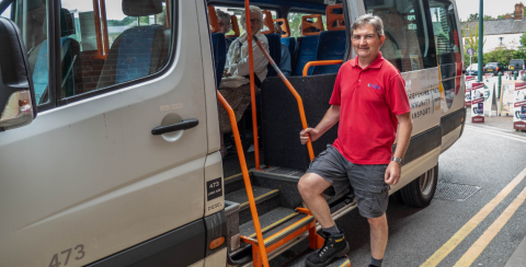 man in red shirt boarding an accessible grey minibus 