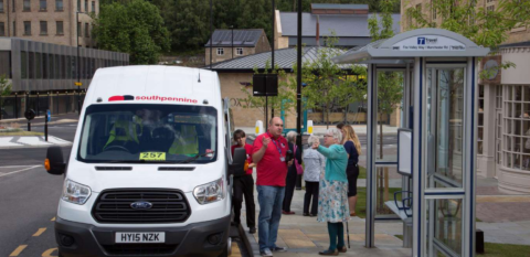 white minibus with red lettering. Staff and passengers talking and giving directions 