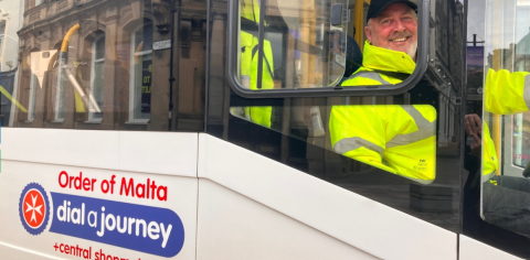 photo showing a minibus driver in hi viz jacket smiling 