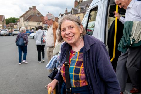 passenger wearing navy blue, smiles while getting off a minibus