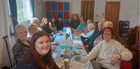 photo shows a group of women of all ages around a table smiling 