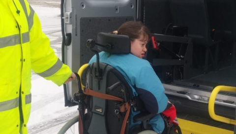 photo shows a driver assisting a passenger with a wheelchair 