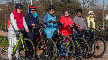 Smiling women stood next to their bikes