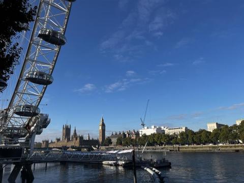 Photograph showing parliament buildings in london from the south bank, blue sky and millennium wheels