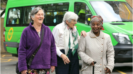 3 women standing in front of a green minibus smiling