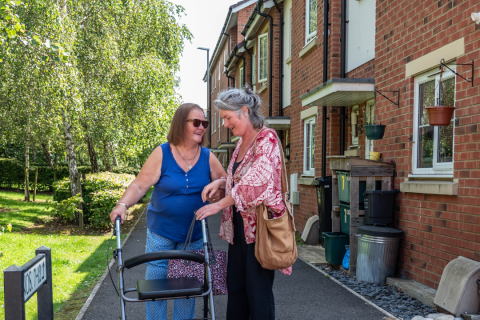 photo showing two people smiling and helping each other on a path