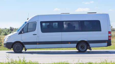 a white minibus drives along a road