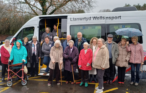 Photo of a variety of people standing in front of a white Llanwrtyd Wells Community Transport minibus