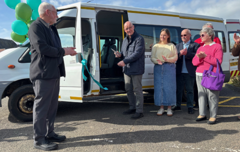 Image of people standing outside the Strathie Hopper minibus, with balloons and a person cutting a ribbon 