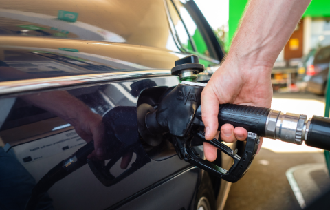 Image of someone's hand putting a petrol pump in to their black car