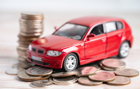 A red car on top of piled up coins