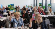 A photo from the CTA Scotland conference of delegates holding the manifesto above their heads