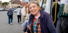 passenger wearing navy blue, smiles while getting off a minibus