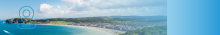 photo of a Welsh seaside town with a graphic location pin in blue and white 