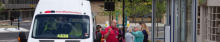 white minibus with red lettering. Staff and passengers talking and giving directions 