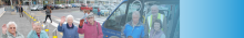 photo of a group of passengers outside a supermarket with shopping trolleys, waving and smiling.