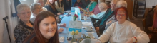 photo shows a group of women of all ages around a table smiling 