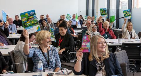 A photo from the CTA Scotland conference of delegates holding the manifesto above their heads