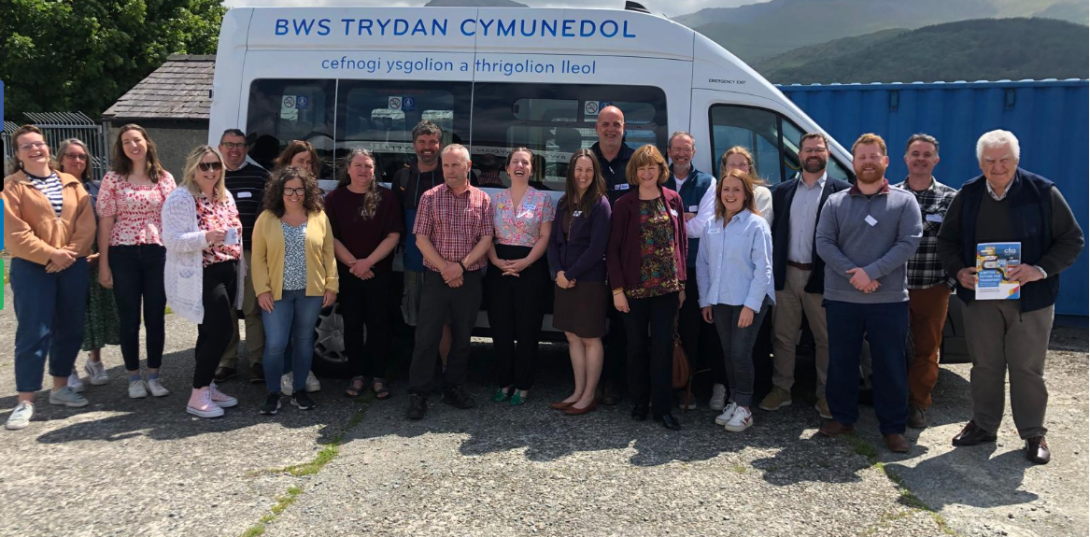 Group of people smiling standing in front of a liveried minibus