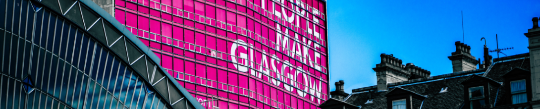 Glasgow building tops with bright pink sign 'people make Glasgow'