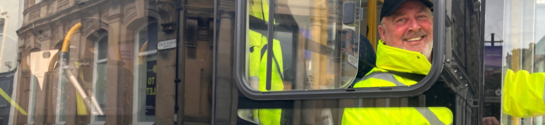 photo showing a minibus driver in hi viz jacket smiling 